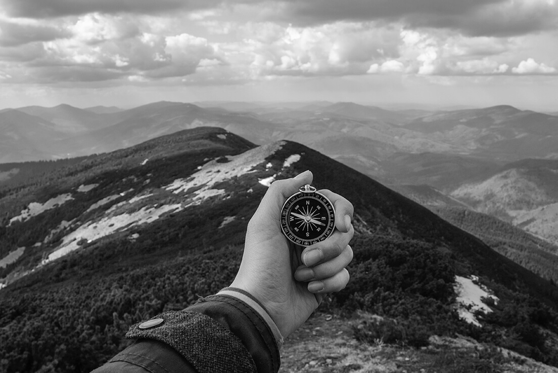 Person on top of a mountain with a compass